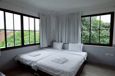 a bedroom with a bed with white sheets and windows at Surachet at 257 Boutique House in Phuket Town