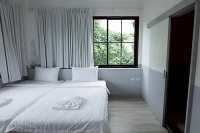 a hotel room with two beds and a window at Surachet at 257 Boutique House in Phuket Town
