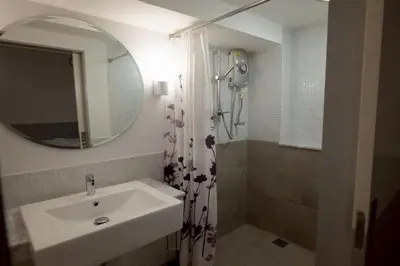 a bathroom with a sink and a shower and a mirror at Surachet at 257 Boutique House in Phuket Town