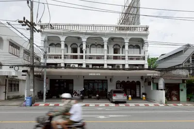 a man riding a motorcycle in front of a building at Surachet at 257 Boutique House in Phuket Town