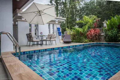 a swimming pool with a table and an umbrella at Baan Ping Tara Private Pool Villa in Ao Nang Beach