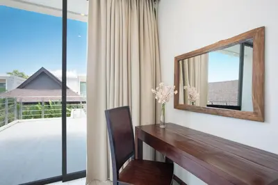 a room with a mirror and a desk with a vase of flowers at Laem Ka Residence by Tropiclook in Rawai Beach
