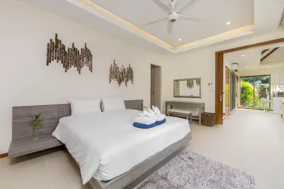 a bedroom with a large white bed and a chandelier at Laem Ka Residence by Tropiclook in Rawai Beach