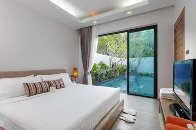 a bedroom with a large bed and a large window at La Ville Phuket Pool Villa in Nai Yang Beach