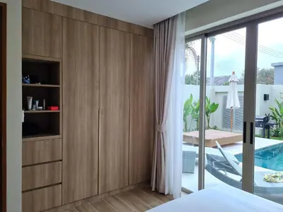 a bedroom with wooden cabinets and a swimming pool at La Ville Phuket Pool Villa in Nai Yang Beach