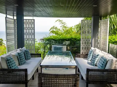 a patio with a table and chairs and the ocean at Villa Saan - SHA Extra Plus in Kamala Beach
