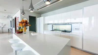 a white kitchen with a large white counter and stools at Villa Paradiso in Nai Thon Beach