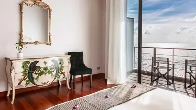 a room with a mirror and a chair and a balcony at Villa Paradiso in Nai Thon Beach