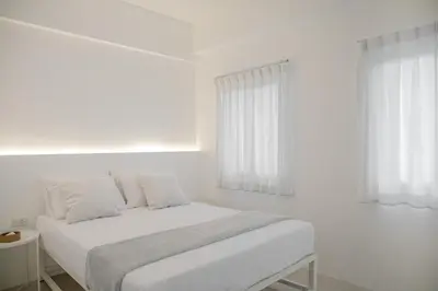 a white bedroom with a bed and two windows at Hao Hostel Phuket in Phuket Town