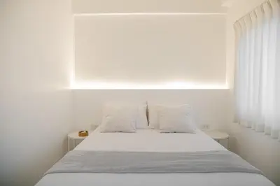 a white bedroom with a bed with white sheets and pillows at Hao Hostel Phuket in Phuket Town