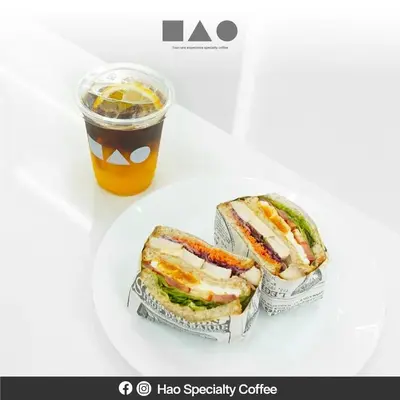 a sandwich on a plate next to a drink at Hao Hostel Phuket in Phuket Town