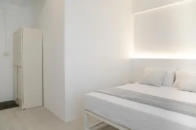 a white bedroom with a bed and a cabinet at Hao Hostel Phuket in Phuket Town