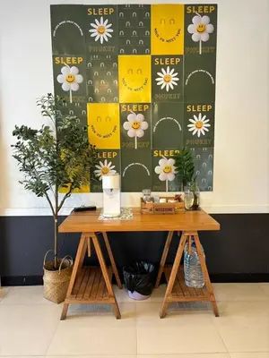 a table with a sign on a wall with flowers at Sleep at Phuket SHA Plus in Phuket Town