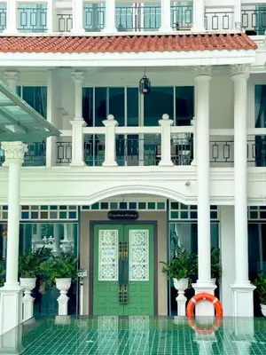 a large white building with a green door at Grand Supicha City Hotel in Phuket Town