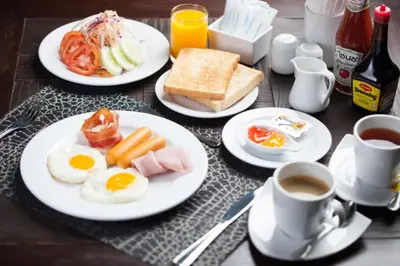 a table with plates of breakfast food and cups of coffee at Grand Supicha City Hotel in Phuket Town