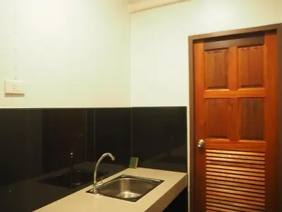 a kitchen with a sink and a wooden door at Coconut Bungalow in Nai Yang Beach