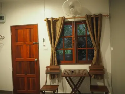 a room with a window and chairs next to a door at Coconut Bungalow in Nai Yang Beach