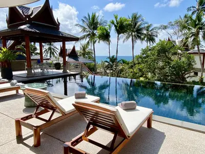 a swimming pool with two lounge chairs next to a resort at Luxury Seaview Villa Surin Beach Phuket in Surin Beach