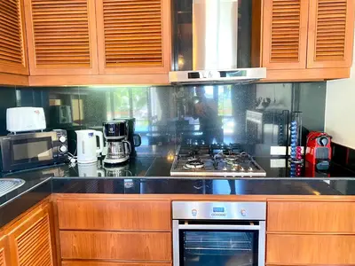 a kitchen with wooden cabinets and a stove top oven at Luxury Seaview Villa Surin Beach Phuket in Surin Beach