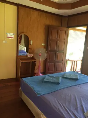 a bedroom with a bed with a blue blanket and a fan at Namtok Bungalows in Ko Yao Noi