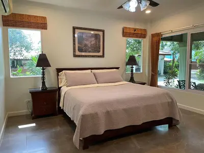 a bedroom with a bed with two lamps and windows at Vacation Garden Villa in Thalang