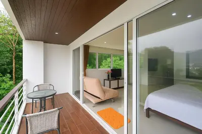 a balcony with a bedroom and a bed and a table at BeststayinPhuket Mountain Poolviews in Patong Beach