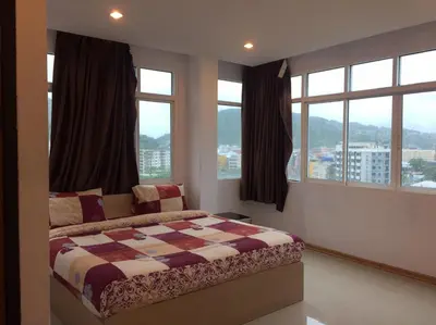a bedroom with a bed and windows with a view at The C Park in Patong Beach