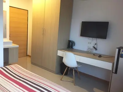 a bedroom with a desk with a television on a wall at The C Park in Patong Beach