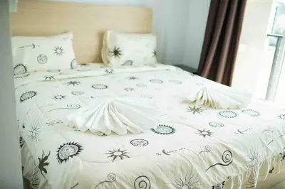 a bed with a white comforter with flowers on it at The C Park in Patong Beach