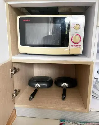 a microwave in a cabinet with two stools underneath it at The C Park in Patong Beach