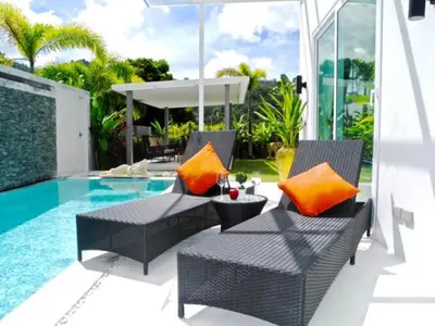 a patio with two chairs with orange pillows next to a pool at Skylight 2 bedrooms Villa in Kamala in Kamala Beach