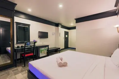 a bedroom with a bed and a chair and a television at Patong Holiday Dream Hotel in Patong Beach