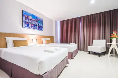 a hotel room with two beds and a chair at Vapa Hotel - SHA Extra Plus in Phuket Town