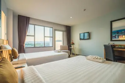 a hotel room with two beds and a window at Vapa Hotel - SHA Extra Plus in Phuket Town