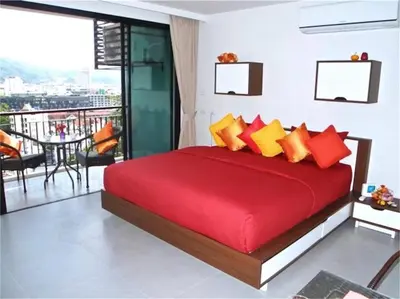 a bedroom with a red bed and a balcony at Bliss Patong 2 bedrooms Apartment in Patong Beach