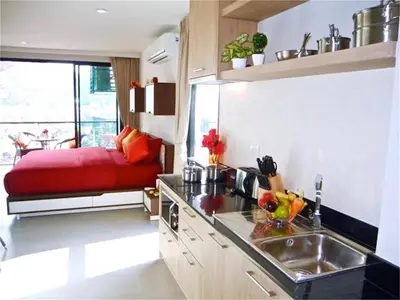 a kitchen with a red couch in the middle of it at Bliss Patong 2 bedrooms Apartment in Patong Beach