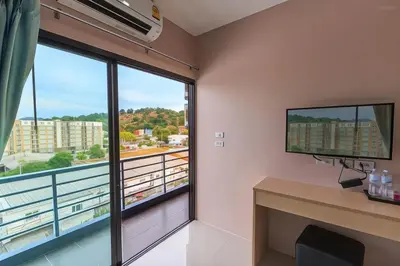 a room with a large window and a desk with a television at JJ Residence Phuket Town in Phuket Town
