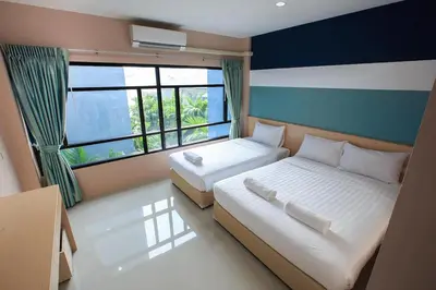 two beds in a room with a large window at JJ Residence Phuket Town in Phuket Town