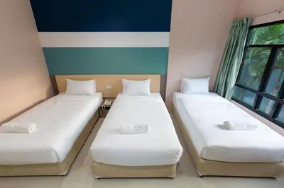 two twin beds in a room with a window at JJ Residence Phuket Town in Phuket Town