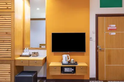 a room with a tv on a yellow wall at Tee Pak Dee Resident Phuket in Phuket Town