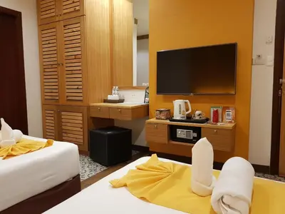 a hotel room with two beds and a flat screen tv at Tee Pak Dee Resident Phuket in Phuket Town