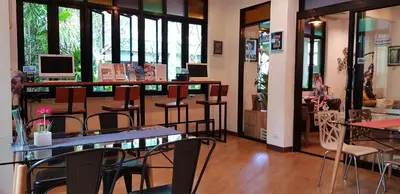 a restaurant with tables and chairs and windows at Tee Pak Dee Resident Phuket in Phuket Town