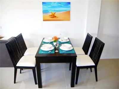a dining room table with chairs and a black table with plates and flowers at Patong Bay Hill 1 bedroom Apartment in Patong Beach