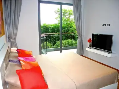 a living room with a couch and a large window at Emerald Patong 1 bedroom Modern Apartment in Patong Beach
