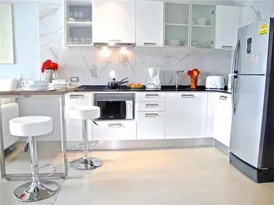 a kitchen with white cabinets and a refrigerator at Emerald Patong 1 bedroom Modern Apartment in Patong Beach