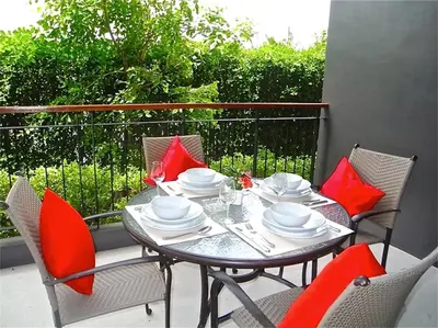 a table and chairs on a balcony with red pillows at Emerald Patong 1 bedroom Modern Apartment in Patong Beach