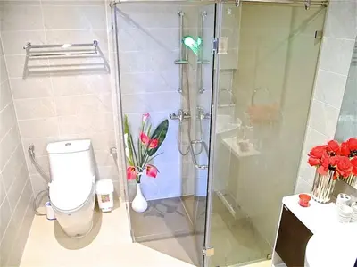 a bathroom with a shower with a toilet and flowers at Emerald Patong 1 bedroom Modern Apartment in Patong Beach