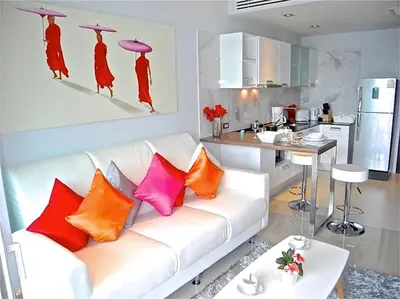 a living room with a white couch with colorful pillows at Emerald Patong 1 bedroom Modern Apartment in Patong Beach
