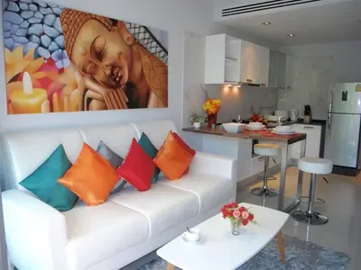 a living room with a white couch with colorful pillows at Emerald Patong 1 bedroom Apartment Garden View in Patong Beach