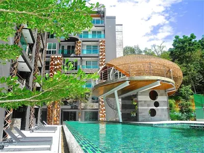 a swimming pool in front of a building with a house at Emerald Patong 1 bedroom Apartment Garden View in Patong Beach